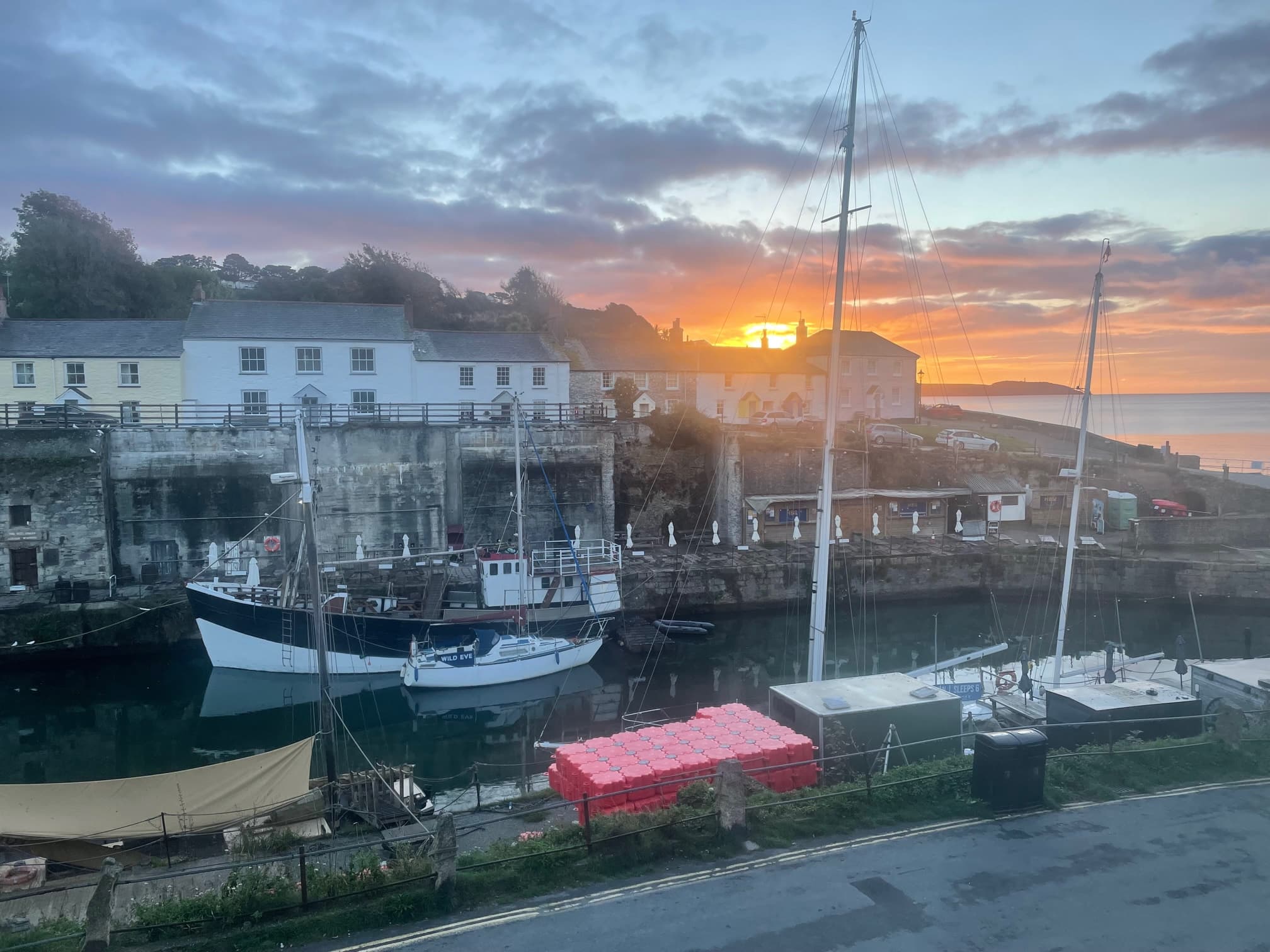 Sunset over boats moored in a Cornish harbour